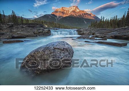 Sunset lights up Mount Fryatt as the Athabasca River flows over Athabasca Falls in Jasper National Park; Alberta, Canada View Large Photo Image Stock Image - Sunset lights up Mount Fryatt as the Athabasca River flows over Athabasca Falls in Jasper National Park; Alberta, Canada. Fotosearch