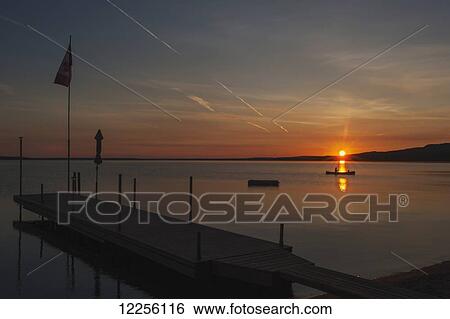 Sunset looking out from a dock on a calm wilderness lake; Ontario, Canada View Large Photo Image Stock Photograph - Sunset looking out from a dock on a calm wilderness lake; Ontario, Canada. Fotosearch