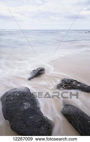 Surf washing over black rocks on beach; Wailua, Kauai, Hawaii, United States of America View Large Photo Image Stock Photo - Surf washing over black rocks on beach; Wailua, Kauai, Hawaii, United States of America. Fotosearch