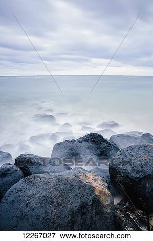 Stock Photo - Surf washing up around rocks and driftwood; Wailua, Kauai, Hawaii, United States of America. Fotosearch