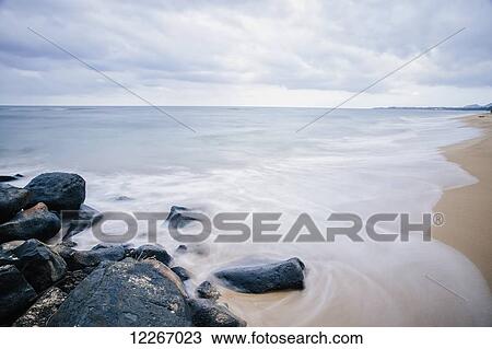 Stock Image - Surf washing up around rocks; Wailua, Kauai, Hawaii, United States of America. Fotosearch