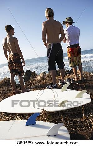 Stock Photo - Surfboards On Ground Behind Three Surfers. Fotosearch