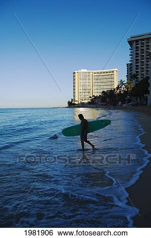 Stock Photograph - Surfer at dawn on Waikiki Beach; Oahu, Hawaii, United States of America. Fotosearch