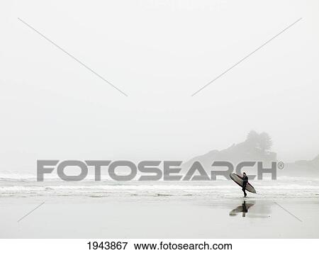 Stock Photo - Surfer Walking On The Beach In Cox Bay; Tofino British Columbia Canada. Fotosearch