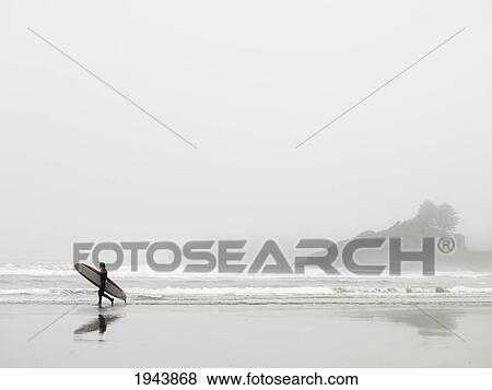 Stock Photo - Surfer Walking On The Beach In Cox Bay; Tofino British Columbia Canada. Fotosearch