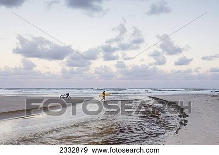 Stock Photo - Surfers On Empty Beach; Byron Bay, New South Wales, Australia. Fotosearch