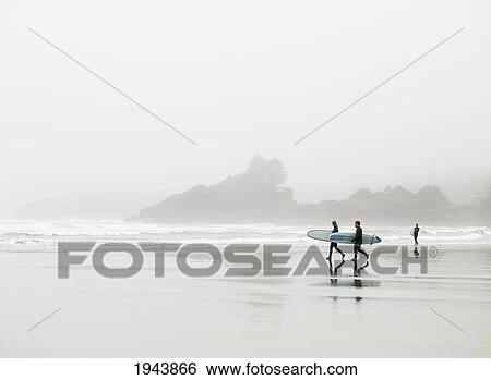 Stock Photograph - Surfers Walking On The Beach In Cox Bay; Tofino British Columbia Canada. Fotosearch