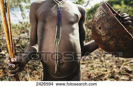 Picture - Suri (Surma) tribe cattle herder with bowl for collecting cattle blood, Omo region, Southwest Ethiopia; Kibish, Ethiopia. Fotosearch