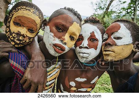Stock Image - Surma children with faces painted with pigment made from powdered coloured stones, Omo region, Southwest Ethiopia; Kibish, Ethiopia. Fotosearch