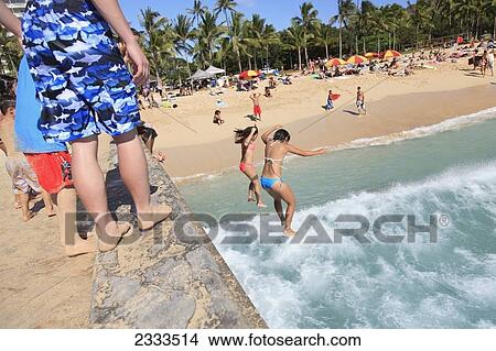 Swimmers jumping off a wall into the ocean waves below at a busy beach; Honolulu, Oahu, Hawaii, United States of America View Large Photo Image Picture - Swimmers jumping off a wall into the ocean waves below at a busy beach; Honolulu, Oahu, Hawaii, United States of America. Fotosearch
