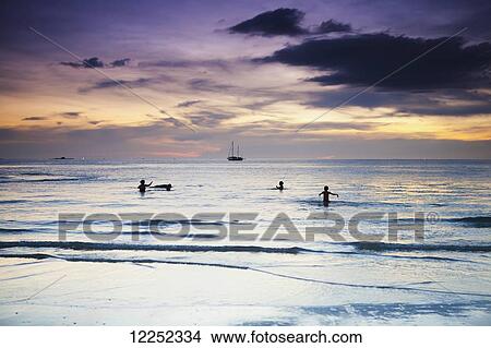 Swimming in the ocean at sunset at Cenang beach; Langkawi, Malaysia View Large Photo Image Picture - Swimming in the ocean at sunset at Cenang beach; Langkawi, Malaysia. Fotosearch