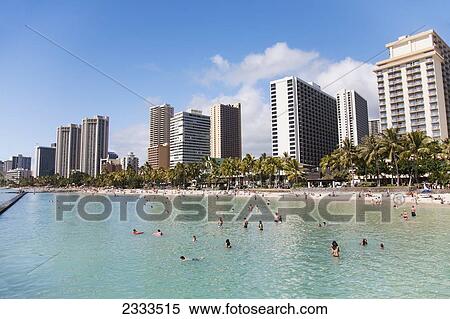 Stock Photography - Swimming in the ocean with condominium buildings along the coast; Honolulu, Oahu, Hawaii, United States of America. Fotosearch