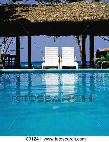 Stock Image - Swimming Pool With White Sun Loungers. Fotosearch