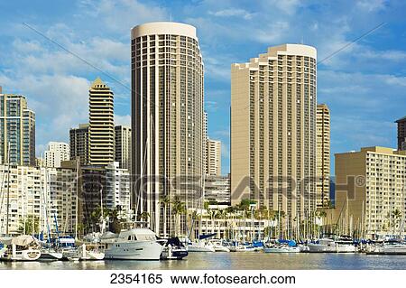 Stock Photography - Tall office buildings and apartments tower over the Honolulu Yacht Harbour; Honolulu, Oahu, Hawaii, United States of America. Fotosearch