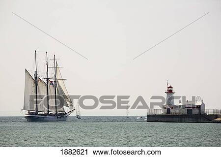 Stock Image - Tall Ship With Sails And A Lighthouse; Port Colborne, Ontario, Canada. Fotosearch