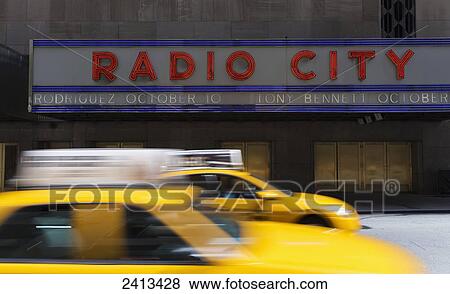 Stock Photo - Taxis passing Radio City Music Hall; New York City, New York, United States of America. Fotosearch