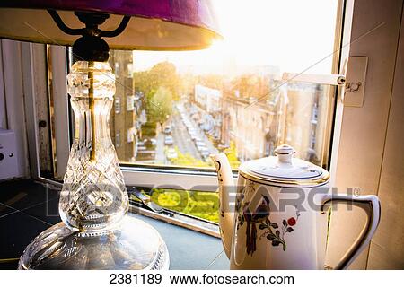 Stock Photo - Teapot and lamp on windowsill in afternoon sun, Baron's Court; West London, England. Fotosearch