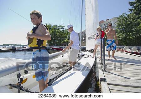 Teenage Boy Wearing A Life Jacket Standing In A Sailboat At The Royal Lake Of The Woods Yacht Club; Kenora Ontario Canada View Large Photo Image Stock Photo - Teenage Boy Wearing A Life Jacket Standing In A Sailboat At The Royal Lake Of The Woods Yacht Club; Kenora Ontario Canada. Fotosearch