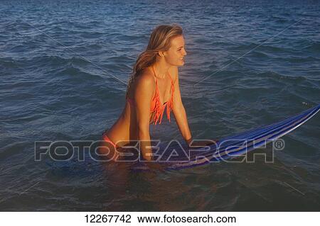 Stock Image - Teenage girl at the beach with her surfboard; Kailua, Island of Hawaii, Hawaii, United States of America. Fotosearch