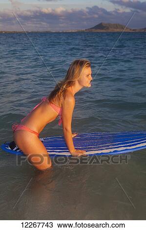 Stock Image - Teenage girl at the beach with her surfboard; Kailua, Island of Hawaii, Hawaii, United States of America. Fotosearch