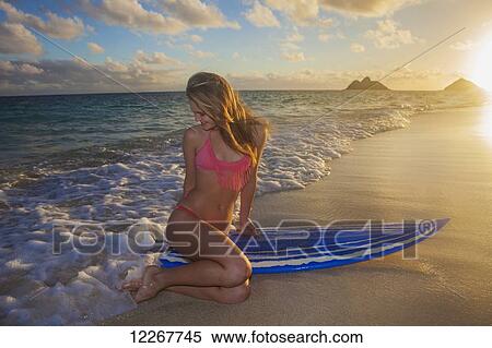 Stock Photography - Teenage girl at the beach with her surfboard; Kailua, Island of Hawaii, Hawaii, United States of America. Fotosearch