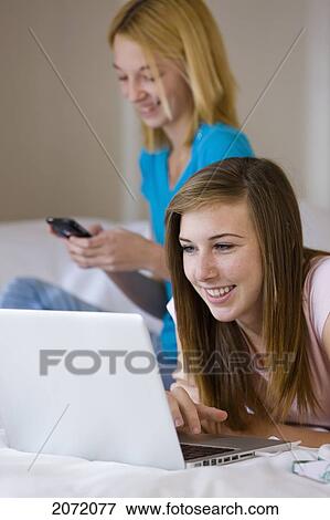 Teenage Girl Lying On Bed Using Laptop While Friend Sends Text Message, Bradford, Ontario View Large Photo Image Stock Photo - Teenage Girl Lying On Bed Using Laptop While Friend Sends Text Message, Bradford, Ontario. Fotosearch