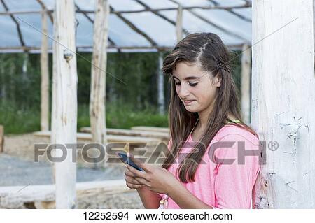 Teenage girl texting on an electronic device; Palmer, Alaska, United States of America View Large Photo Image Picture - Teenage girl texting on an electronic device; Palmer, Alaska, United States of America. Fotosearch