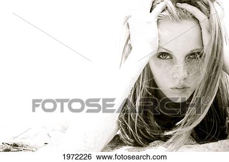 Stock Photograph - Teenage Girl With Freckles And Red Hair Lays In The Sand At The Beach.. Fotosearch