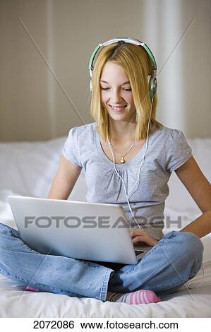 Teenage Girl With Headphones Sitting On Bed Using Laptop, Bradford, Ontario View Large Photo Image Stock Photograph - Teenage Girl With Headphones Sitting On Bed Using Laptop, Bradford, Ontario. Fotosearch