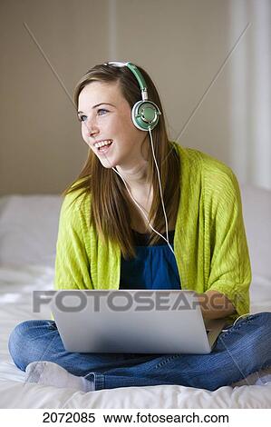 Teenage Girl With Headphones Sitting On Bed Using Laptop, Bradford, Ontario View Large Photo Image Stock Photography - Teenage Girl With Headphones Sitting On Bed Using Laptop, Bradford, Ontario. Fotosearch