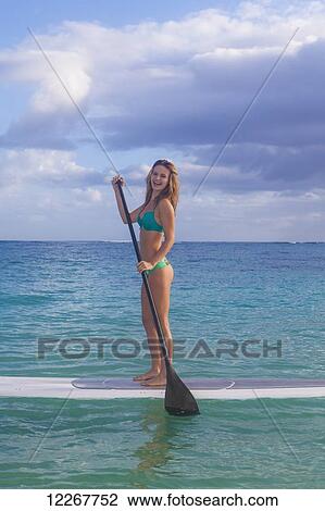 Stock Image - Teenage girl with her paddle board; Kailua, Island of Hawaii, Hawaii, United States of America. Fotosearch