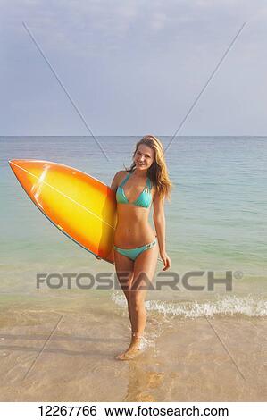 Stock Photograph - Teenage girl with her surfboard; Kailua, Island of Hawaii, Hawaii, United States of America. Fotosearch