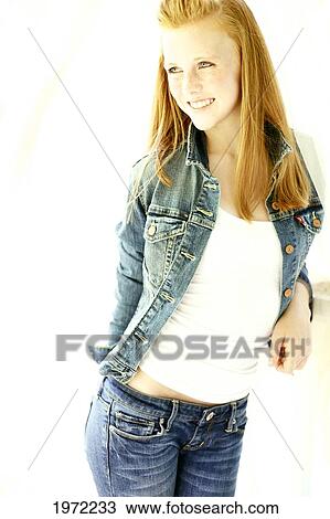 Stock Image - Teenage Girl With Red Hair And Freckles Models Her Denim Fashion In The Studio.. Fotosearch