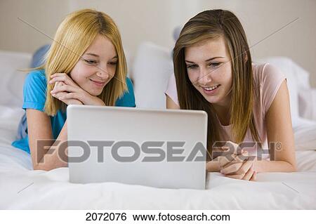 Stock Photograph - Teenage Girls Lying On Bed Using Laptop, Bradford, Ontario. Fotosearch