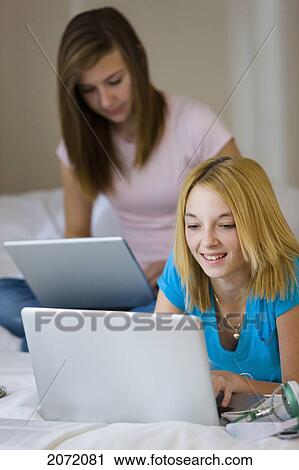 Stock Image - Teenage Girls On Bed Using Laptops, Bradford, Ontario. Fotosearch