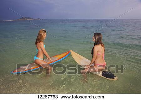 Stock Image - Teenage sisters with their surfboards; Kailua, Island of Hawaii, Hawaii, United States of America. Fotosearch