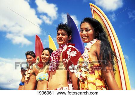 Stock Image - Teens Standing With Colorful Surfboards Along Beach. Fotosearch