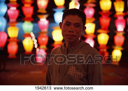 Stock Image - Thai Man Stands In Front Of Chinese Lanterns; Chiang Mai Thailand. Fotosearch