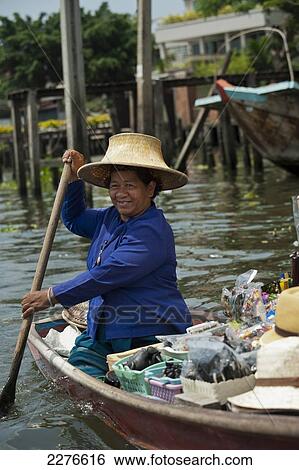 Stock Photograph - Thai woman in small river boat selling goods; Bangkok, Thailand. Fotosearch