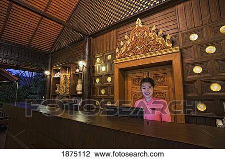 Stock Image - Thailand; A Female Worker At The Desk Of An Outdoor Hotel Lobby. Fotosearch