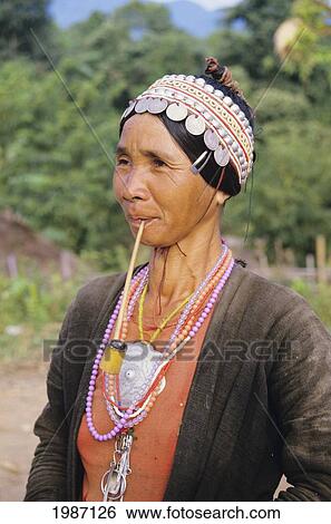 Stock Photograph - Thailand, Akha Village Near Ching Mai, Close-Up Sideview Of Native Woman With Pipe In Mouth. Editorial Use Only.. Fotosearch