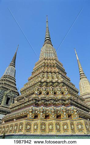 Stock Image - Thailand, Bangkok, Colorful Pointed Steeples Against Clear Blue Sky; Wat Po. Fotosearch