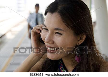 Thailand, Bangkok, Thai Woman Talking On Cell Phone At Train Station. View Large Photo Image Stock Image - Thailand, Bangkok, Thai Woman Talking On Cell Phone At Train Station.. Fotosearch