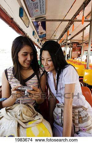 Picture - Thailand, Bangkok, Thai Women Looking At The Back Of A Digital Camera.. Fotosearch