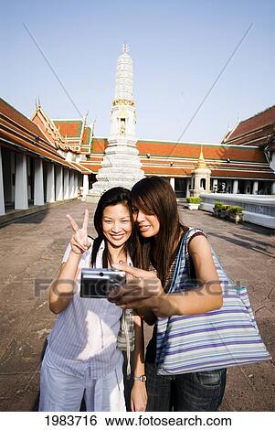 Stock Photograph - Thailand, Bangkok, Thai Women Take A Photo Of Themselves At A Temple.. Fotosearch