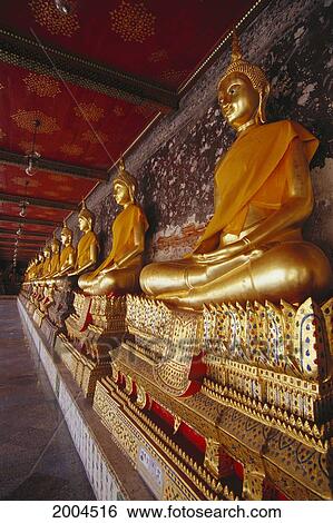 Stock Photograph - Thailand, Bangkok, Wat Suthat Front Angle Of Golden Statues Bodhisattva With Orange Sash. Fotosearch