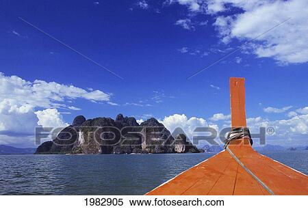 Stock Photography - Thailand, bow of red longtail boat in foreground; Phagna Bay, View from ocean of tropical islands. Fotosearch