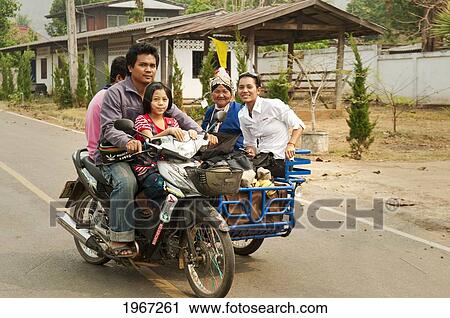 Stock Image - Thailand, Chiang Mai Province, Family Riding Motorcycle And Sidecar Through Village Along Mae Tang River.. Fotosearch