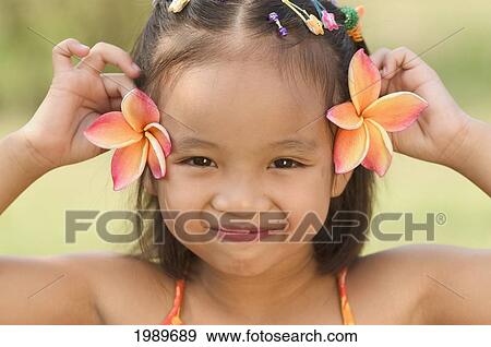 Stock Photo - Thailand, Nong Bai Lumphu, Five Year Old Asian Girl With Plumeria Flowers Behind Her Ears.. Fotosearch