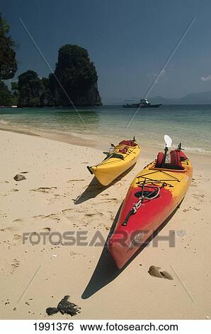 Stock Photograph - Thailand, Phang Nga Bay, Colorful Sea Kayaks On Beach With Rocks And Blue Ocean Behind.. Fotosearch